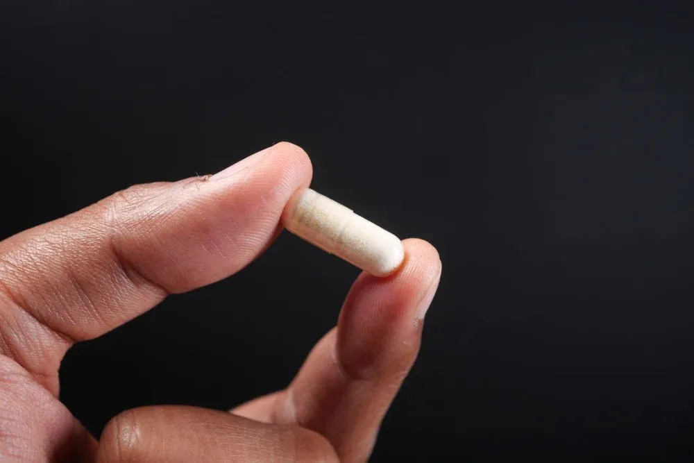 close up of man hand holding capsule against blc
