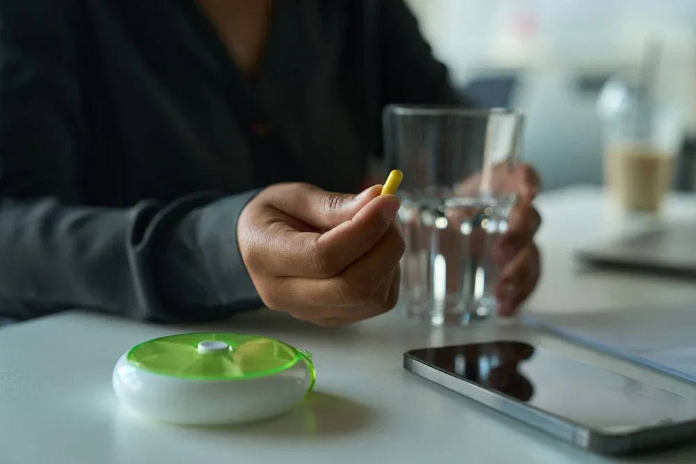 multiracial female sits at a table and holds a pill